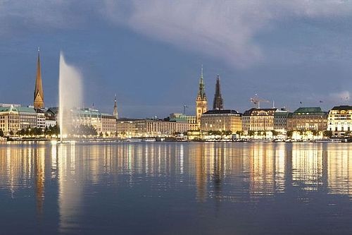 View from the Alster towards Jungfernstieg at night. The lights are being reflected in the water.