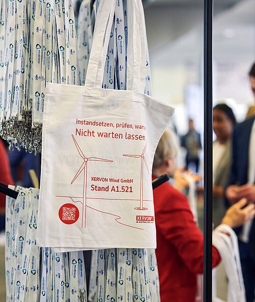 A stand with lanyards and cloth bags with sponsors from WindEnergy Hamburg